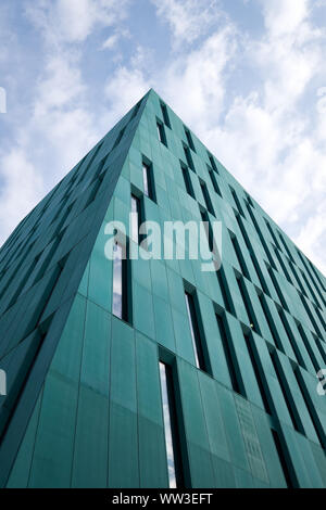 Minimal View from bottom of generic green sky scraper looking at pointy corner into a cloudscape Stock Photo