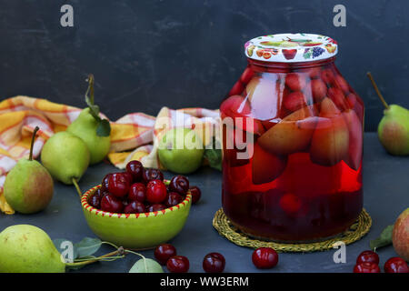 Compote of pears and cherries in jar on dark background, harvest for the winter, horizontal orientation, close-up Stock Photo