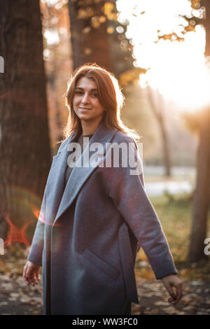Pretty girl walking in autumn park. Beautiful autumn sunny weather. Young woman enjoying fall. Women fashion. Autumn holidays. People, autumn and life