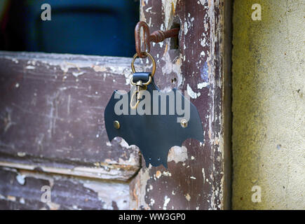 Leather keychain in Bat shape and old key in wooden door. - image Stock Photo