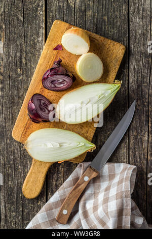 Halved fresh bulbs. Cut onions and knife on old wooden table. Top view. Stock Photo