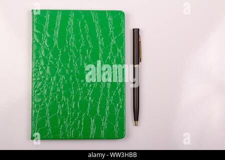 Green notebook with pen on white background Stock Photo