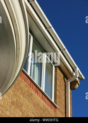 Abstract photo of verticals, horizontals and curves in white pvc on a modern house elevation looking up towards a very blue sky Stock Photo
