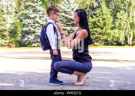 Young brunette mom escorts her first-grader's son to school Stock Photo