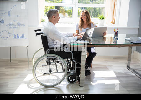 Two Workers Using Laptop Working Together At Office Stock Photo