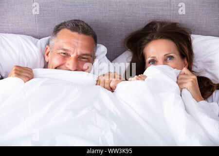 High Angle View Of An Couple Trying To Hide In Blanket Stock Photo