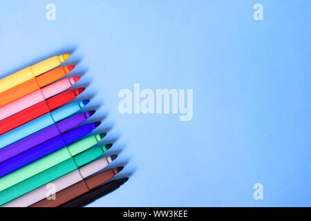 Open multicolored markers closeup on a blue background. Concept back to school. Place for text. Stock Photo