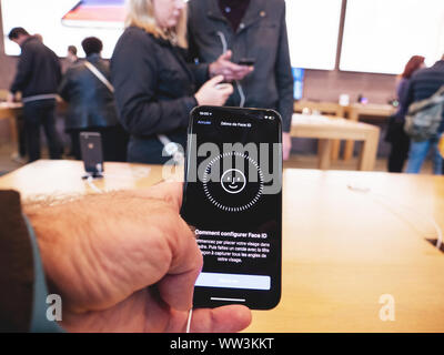 Paris, France - Nov 3, 2017: Customers admiring inside Apple Store the latest professional iPhone smartphone manufactured by Apple Computers testing Face ID Stock Photo