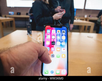 Paris, France - Nov 3, 2017: Man hand admiring inside Apple Store the latest professional iPhone smartphone manufactured by Apple Computers Stock Photo