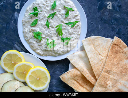 Famous traditional Arabic cuisine - dip Baba ganoush with pita bread and fresh lemon. Flat lay, top view. Baba ganoush