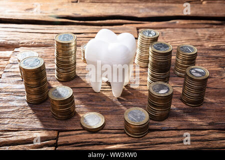 White Healthy Human Tooth And Stacked Coins On Wooden Desk Stock Photo