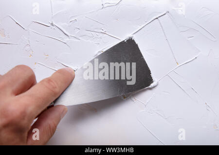 Close-up Of Painter's Hand Puttied Wall Using A Paint Scraper Stock Photo