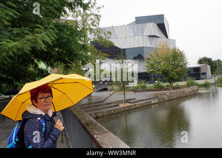 Frau mit gelbem Regenschirm vor Science Center Heilbronn am Neckar, Baden-Würtemberg, Deutschland Stock Photo