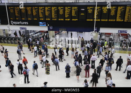 August 2019. Commuters at the main concourse of London Waterloo train station walking past and checking the large departures board, London, UK Stock Photo