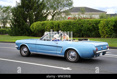 Berlin, CT USA. Sept 2019. Proud American couple driving a classic 1965 Ford Mustang Convertible with a cheeseburger in hand on a fine New England aft Stock Photo