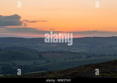 Red setting sun over rolling fields of Shropshire in United Kingdom Stock Photo