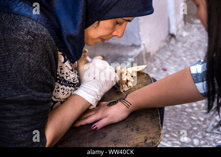 A Spanish woman painting a henna tattoo on a woman's arm; Alcaiceria Market, Granada, Spain. Stock Photo