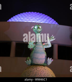 Epcot Center smiling and lighted Imagination Dragon at night, with the Epcot Spaceship Earth sphere in background. lit in purple. Stock Photo