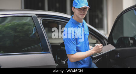 Young delivery man checking the products to customer while standing right next to his car. Stock Photo