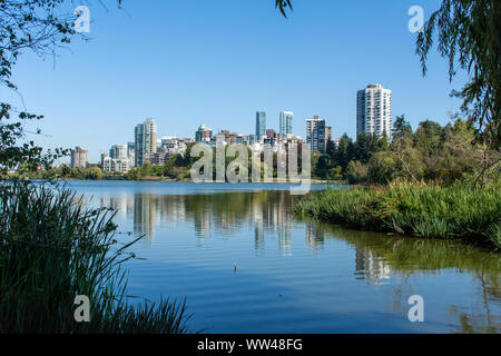 Lost Lagoon in Stanley Park in Vancouver, British Columbia, Canada looking towards downtown urban apartments near the beautiful summer nature. Stock Photo