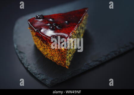 Cake with fruity cream and pistachio decorated with nuts, isolated on black stone. Stock Photo