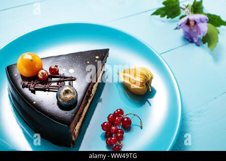 Chocolate cake with decoration and fruits on blue wooden background. Stock Photo