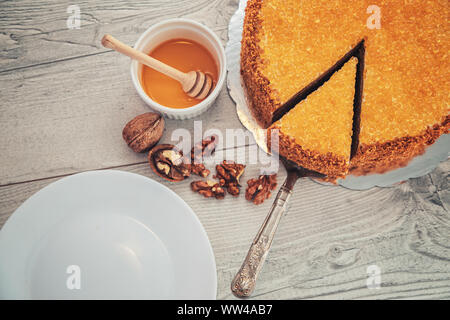 Cake with honey, walnuts, cinnamon and golden pearls isolated over wood background Stock Photo