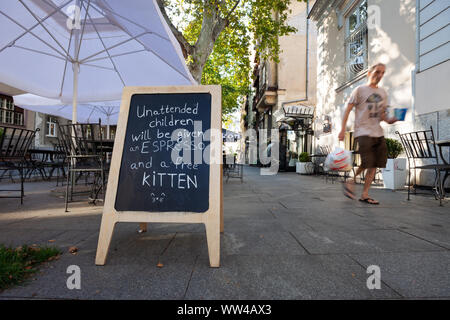 Humorous sign outside a cafe in Belgrade, Serbia with passerby Stock Photo