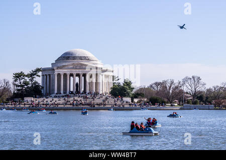 WASHINGTON, D.C. - APRIL 6, 2014: People having fun in paddle boats in the tidal basin, with the Jefferson Memorial and an airplane taking off. Stock Photo