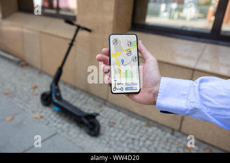 Young Man Using App To Rent Electric Scooter Stock Photo