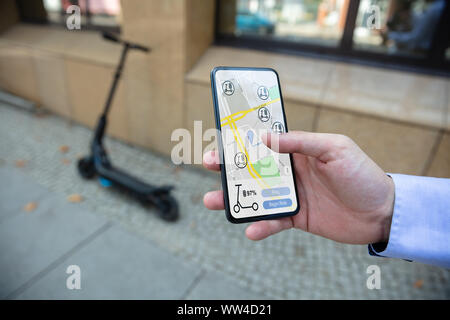 Young Man Using App To Rent Electric Scooter Stock Photo