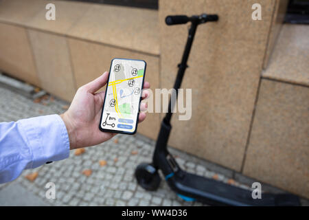 Young Man Using App To Rent Electric Scooter Stock Photo