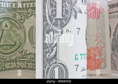 American currency - one-dollar and hundred-dollar bills and Vietnamese 500 dong are on a light surface. Stock Photo