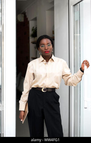 Young african woman is going away from cafe after her coffee break. Stock Photo