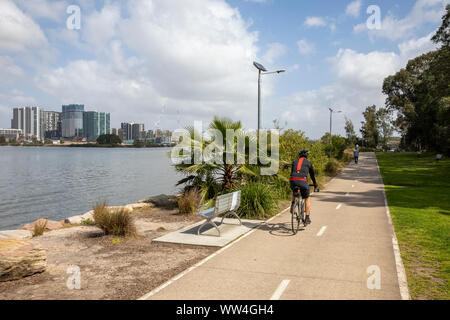 Cyclist riding through Memorial park in Meadowbank Sydney, wentworth point apartments in the distance,Sydney,Australia Stock Photo