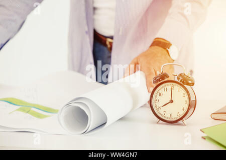 engineer working times clock looking building plan on desk in the morning day Stock Photo