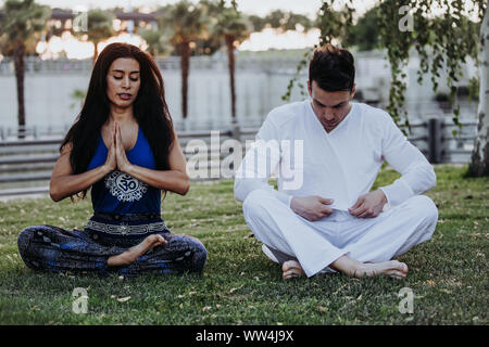Caucasian man and Latin woman meditate in a park in Madrid. Concentration and relaxation in couple. Stock Photo