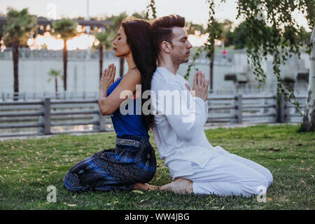 Caucasian man and Latin woman meditate in a park in Madrid. Concentration and relaxation in couple. Stock Photo