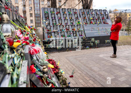 Woman in a red coat standing in front of the Euromaidan Memorial, Kyiv, Ukraine Stock Photo