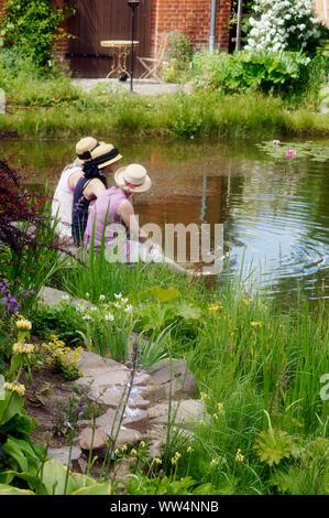 Three singers sitting at a garden pond at the festival of the gardens on the 15th of June, 2014 in Biesendorf, Stock Photo