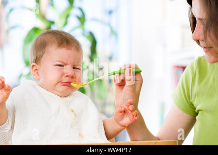 Unhappy baby boy refusing to eat food. Stock Photo