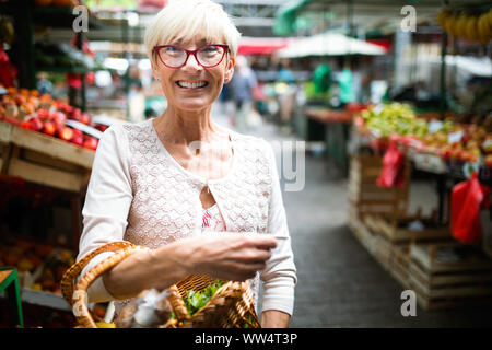 Only the best fruits and vegetables. Beautiful mature woman buying fresh food on market Stock Photo