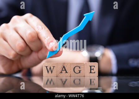 Person's Hand Holding Growth Arrow Near Wage Word Stock Photo
