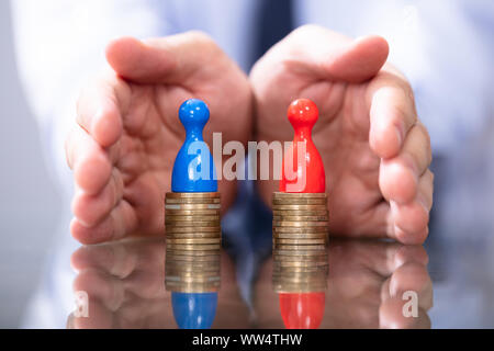 Man Protecting To Coin Stacks. Equal Pay For Men And Women Stock Photo