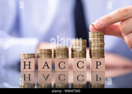 Closeup Photo Of Man Stacking Coins On HACCP Letters Stock Photo