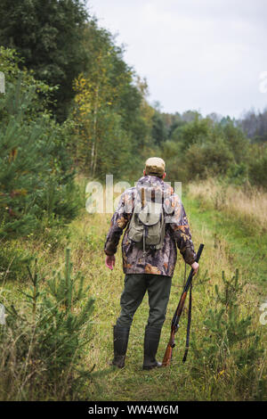 Hunter with a backpack and a hunting gun in the autumn forest. Stock Photo