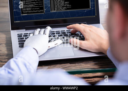 Man With Prosthetic Hand Working On Laptop. Artificial Limb Stock Photo