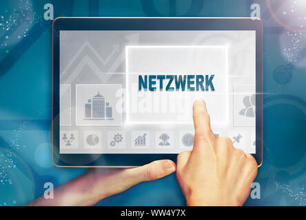 A hand holiding a computer tablet and pressing a Network 'Netzwerk' business concept. Stock Photo