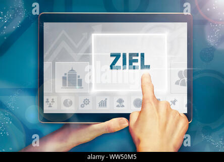 A hand holiding a computer tablet and pressing a Aim 'Ziel' business concept. Stock Photo