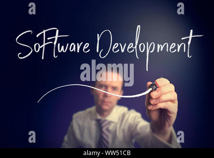 A businessman writing a Software Development concept with a white pen on a clear screen. Stock Photo